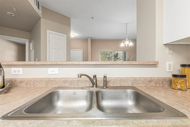 room details featuring an inviting chandelier, light countertops, visible vents, and a sink