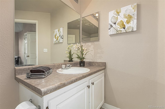 half bathroom with vanity and a textured wall