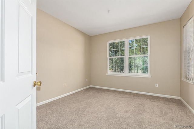 carpeted spare room featuring baseboards