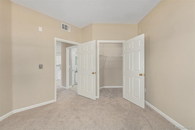 unfurnished bedroom featuring a closet, visible vents, light colored carpet, and baseboards