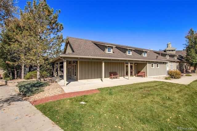 view of front of house with board and batten siding, a front lawn, a patio, and roof with shingles