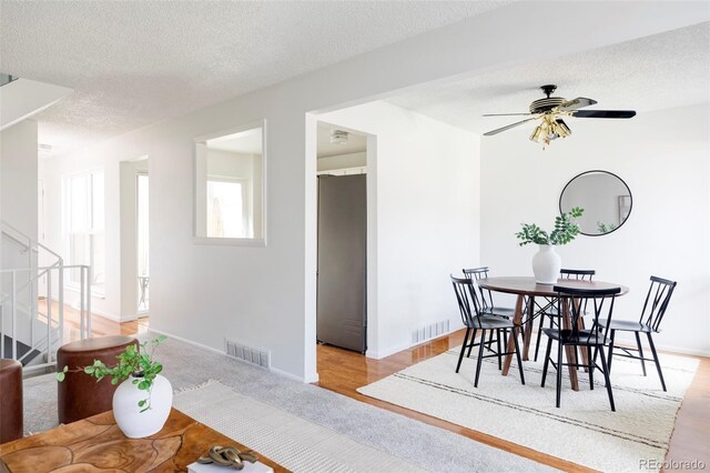 9453 W Utah Pl, Lakewood, CO 80232 - dining space with a textured ceiling, stairway, light carpet, a ceiling fan, and baseboards