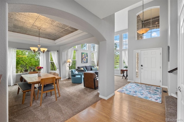 dining room with a tray ceiling, a chandelier, plenty of natural light, and wood finished floors