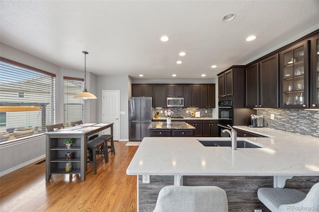 kitchen featuring stainless steel appliances, dark brown cabinets, a kitchen island, baseboards, and tasteful backsplash
