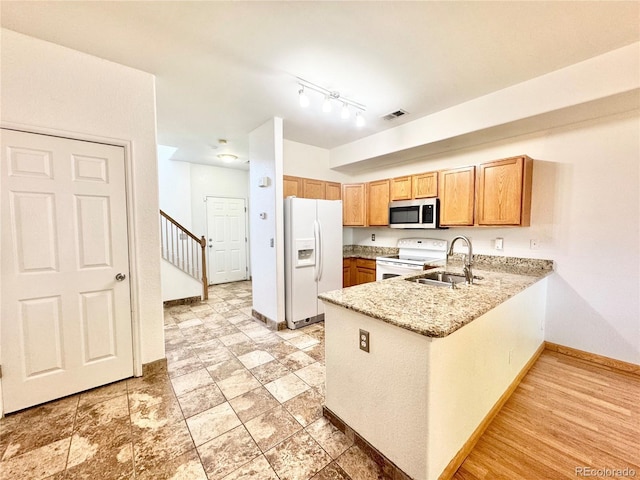 2247 Coronado Pkwy N # D, Denver, CO 80229 - kitchen featuring white appliances, a sink, a peninsula, baseboards, and light stone counters