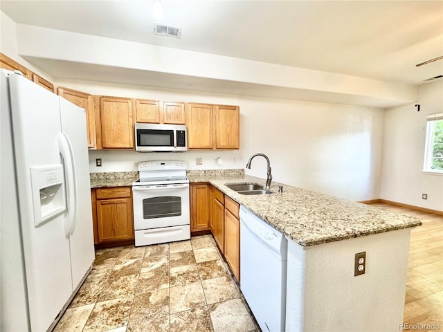 2247 Coronado Pkwy N # D, Denver, CO 80229 - kitchen with white appliances, a sink, a peninsula, and light stone countertops