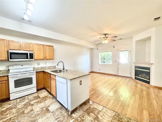 2247 Coronado Pkwy N # D, Denver, CO 80229 - kitchen with white appliances, a sink, a ceiling fan, a peninsula, and a glass covered fireplace