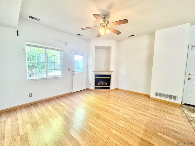 2247 Coronado Pkwy N # D, Denver, CO 80229 - unfurnished living room with wood finished floors, a ceiling fan, a glass covered fireplace, and baseboards
