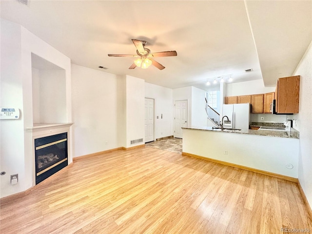 2247 Coronado Pkwy N # D, Denver, CO 80229 - unfurnished living room featuring light wood-style flooring, a ceiling fan, a glass covered fireplace, and baseboards
