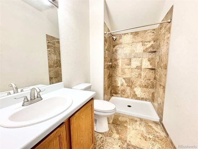 2247 Coronado Pkwy N # D, Denver, CO 80229 - full bath featuring toilet, tiled shower, vanity, stone finish floors, and a textured wall