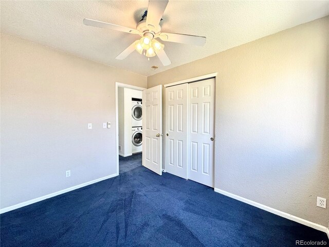 2247 Coronado Pkwy N # D, Denver, CO 80229 - unfurnished bedroom with stacked washing machine and dryer, a closet, baseboards, dark carpet, and a ceiling fan
