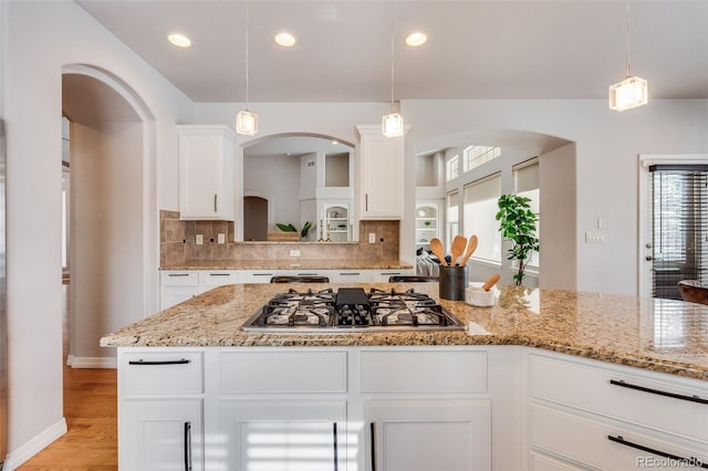 kitchen with hanging light fixtures, light wood finished floors, stainless steel gas stovetop, and white cabinets