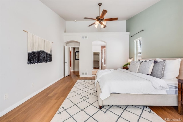 bedroom with visible vents, arched walkways, and wood finished floors