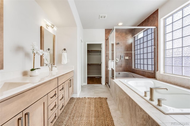 bathroom with a healthy amount of sunlight, a stall shower, double vanity, and a garden tub