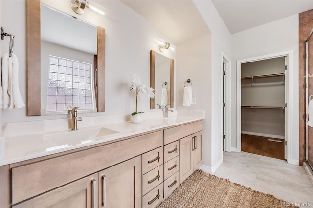 bathroom featuring double vanity, a stall shower, a spacious closet, and a sink