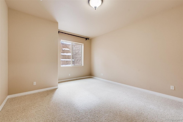 carpeted spare room featuring baseboards