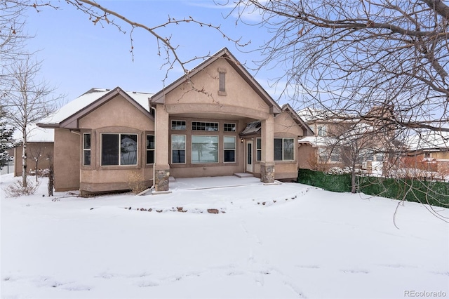 snow covered house featuring stucco siding