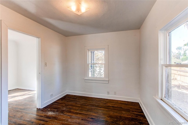 unfurnished room with a textured ceiling and dark wood-type flooring