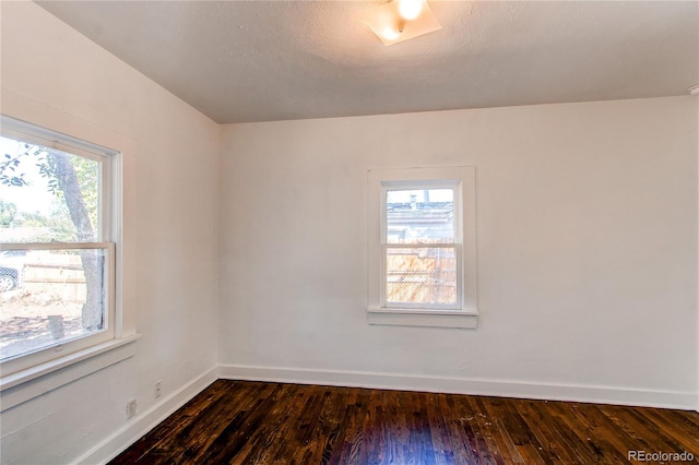 unfurnished room with a textured ceiling, dark wood-type flooring, and a wealth of natural light