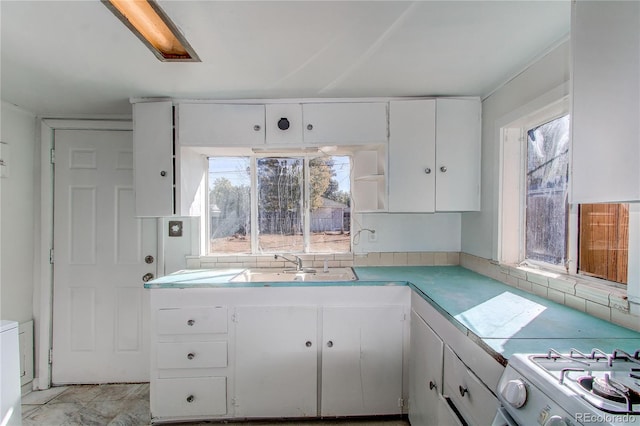 kitchen featuring white stove, decorative backsplash, sink, and white cabinets