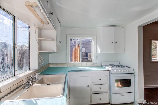 kitchen featuring white cabinets, white gas range, a healthy amount of sunlight, and sink