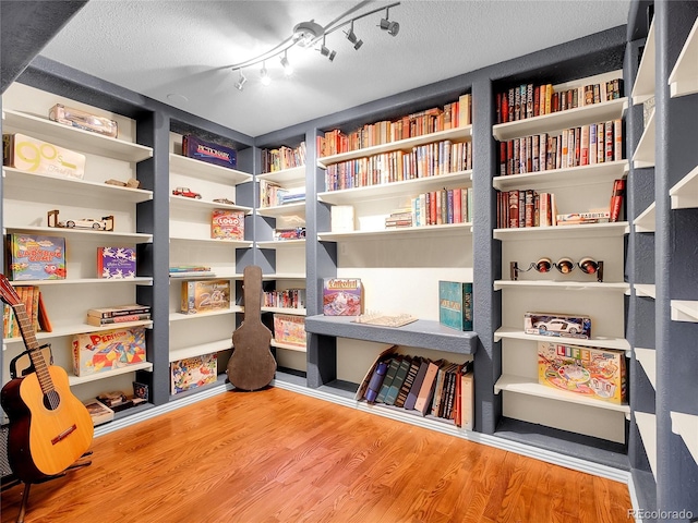 13133 Regulus Dr, Lone Tree, CO 80124 - living area featuring bookshelves, wood finished floors, a textured ceiling, and rail lighting