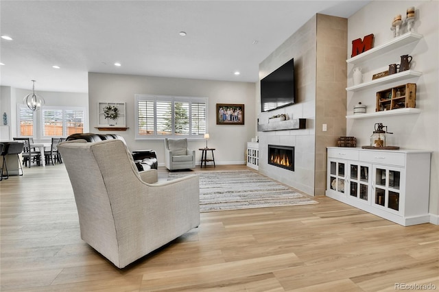 living area with light wood finished floors, a wealth of natural light, and a notable chandelier