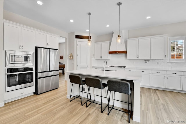 kitchen featuring a kitchen bar, white cabinetry, light wood-type flooring, light countertops, and appliances with stainless steel finishes