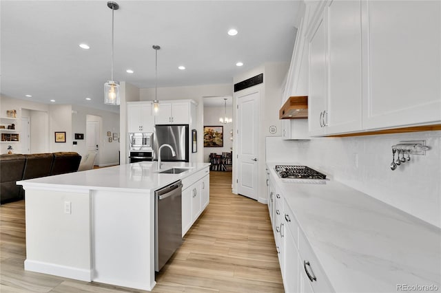 kitchen featuring a sink, light wood-style flooring, decorative backsplash, and appliances with stainless steel finishes