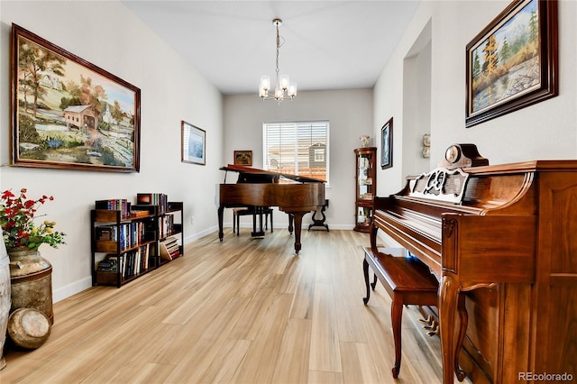 sitting room featuring baseboards, a notable chandelier, and light wood-type flooring