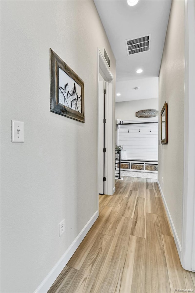 corridor featuring light wood-type flooring, visible vents, and baseboards