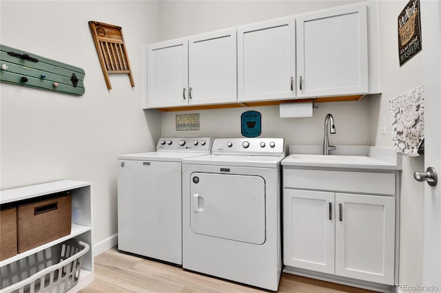 washroom featuring a sink, cabinet space, independent washer and dryer, light wood-type flooring, and baseboards