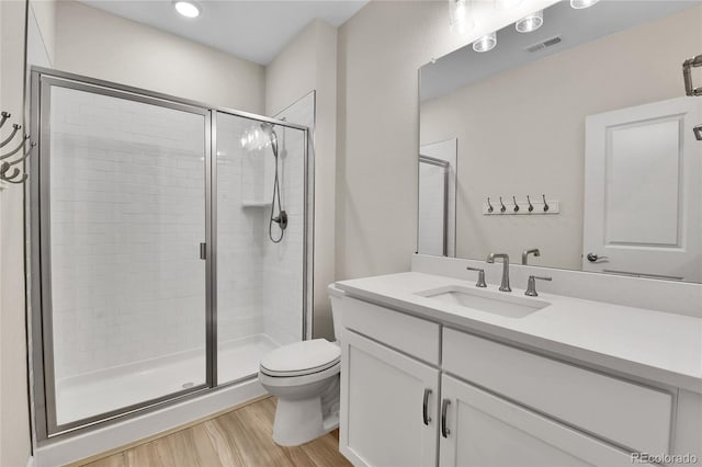 bathroom featuring a shower stall, toilet, visible vents, and wood finished floors