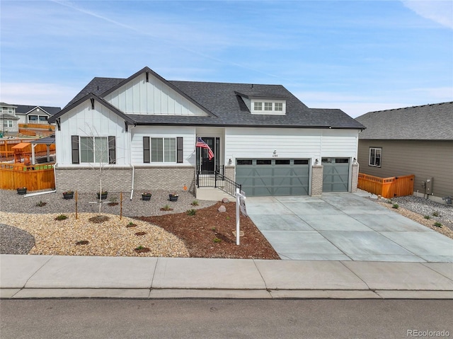 view of front of house with board and batten siding, brick siding, fence, an attached garage, and concrete driveway