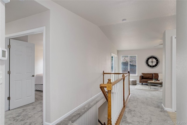 corridor with lofted ceiling and light colored carpet