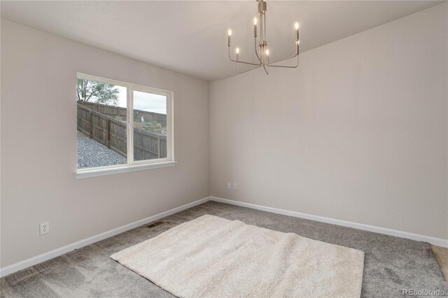 empty room with an inviting chandelier and carpet floors