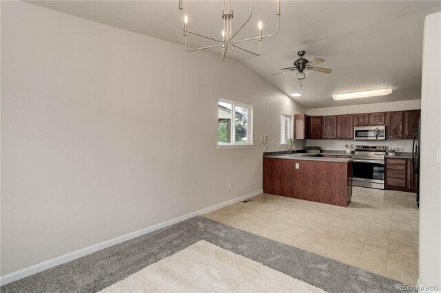 kitchen featuring ceiling fan with notable chandelier, kitchen peninsula, stainless steel appliances, lofted ceiling, and decorative light fixtures