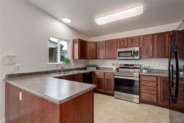 kitchen with appliances with stainless steel finishes, kitchen peninsula, sink, and lofted ceiling