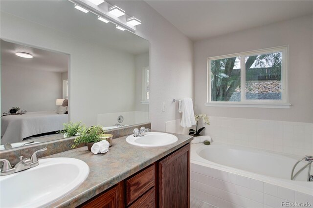 bathroom featuring tiled tub and vanity