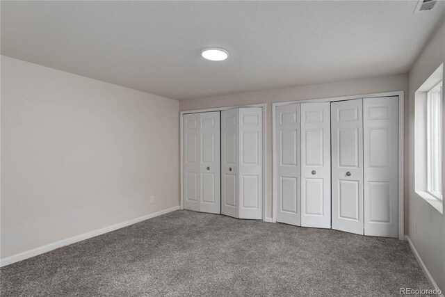 unfurnished bedroom featuring two closets and carpet flooring