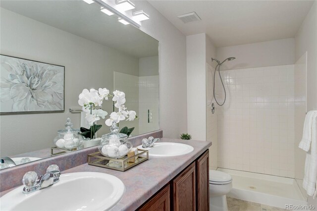 bathroom featuring a tile shower, a skylight, vanity, and toilet