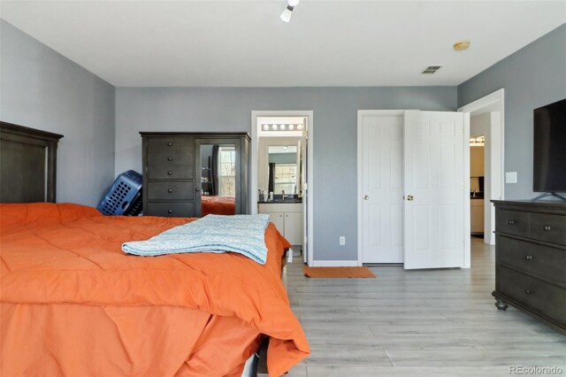 bedroom with connected bathroom and light wood-type flooring