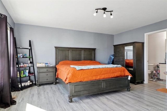 bedroom featuring connected bathroom and light hardwood / wood-style flooring