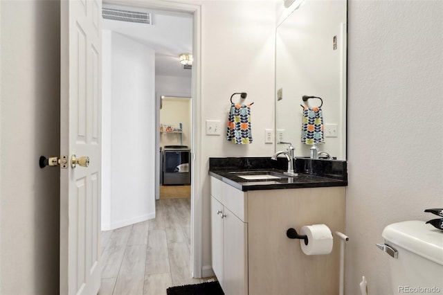 bathroom with hardwood / wood-style floors, vanity, and toilet