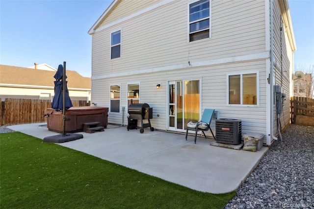 rear view of property featuring a hot tub, central AC unit, and a patio area