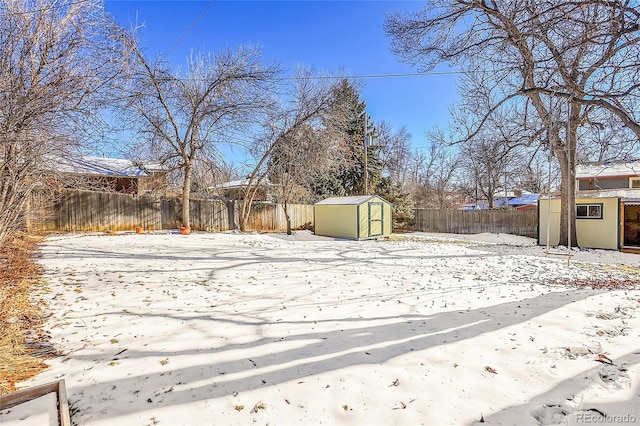 yard covered in snow featuring a storage shed