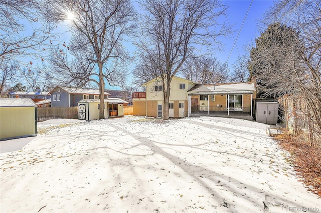 snow covered rear of property featuring a shed