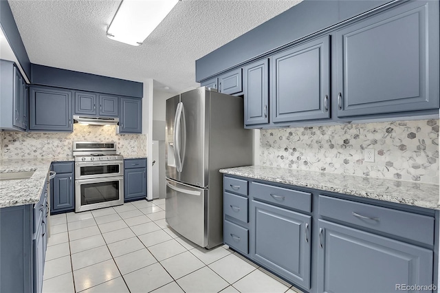 kitchen with stainless steel appliances, blue cabinets, sink, and light tile patterned floors