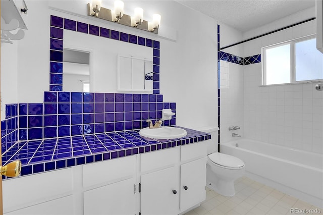 full bathroom featuring backsplash, tiled shower / bath combo, vanity, toilet, and a textured ceiling