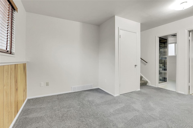 unfurnished room featuring stairway, carpet flooring, visible vents, and baseboards